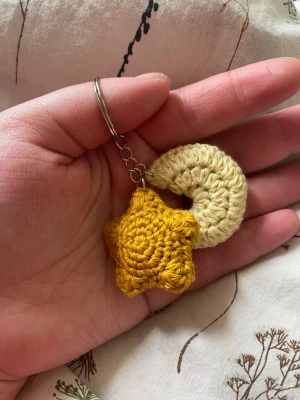 Virkad nyckelring stjärna och måne - Handgjord nyckelring med motiv av stjärna och måne. Perfekt som söt accessoar till väskan eller nycklarna. Virkad i 100% bomull. Från ett djur- och rökfritt hem.