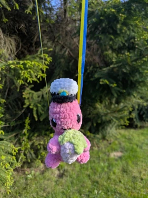 Studentdino rosa med mössa - Söt rosa studentdino i mjukt plyschmaterial, med vit och svart studentmössa och blågula band. Nallen håller i ett grönt och vitt hjärta. Perfekt som present till studenten!