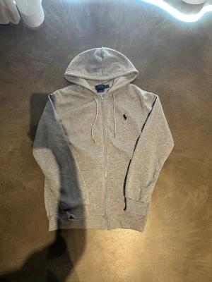 Grå hoodie med luva - Snygg grå hoodie med luva. Perfekt för en avslappnad och stilren look. Mjuk bomullsblandning som känns skön mot huden. Använd några gånger med försiktigthet men annars helt ny. Priset kan diskuteras. Hör av er vid frågor!😊