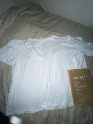 2 st Vita t-shirts från Ravelli - Två klassiska vita t-shirts från Ravelli med rund hals och korta ärmar. Perfekta för en clean och enkel stil. Materialet känns mjukt och bekvämt mot huden. Säljs tillsammans i ett paket.
