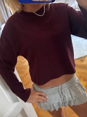 Vinröd croppad tröja - Säljer en vinröd croppad tröja med rund halsringning och långa ärmar. Tröjan har en enkel, stilren design och är perfekt för dig som gillar en avslappnad men trendig look. Materialet ser mjukt och bekvämt ut.