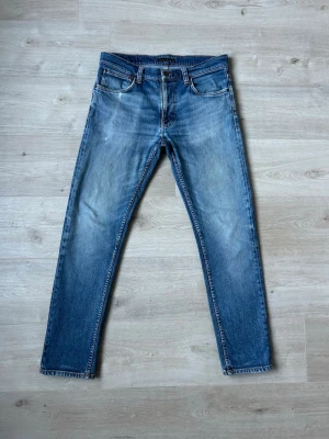 Blåa Nudie Lean Dean Jeans Storlek W32 L32 - Mycket fina Nudie Jeans i blå färg. Jeansen är i mycket bra skick och sparsamt använda. |  Äkta som allt annat jag säljer! ✅ |  Storlek: W32 L32  Skick: Mycket Bra Skick - Har ett väldigt litet hål/slitning vid gylfen (SE SISTA BILD) | Färg: Blå | Märke: Nudie | Modell: Jeans |   Hör gärna av dig vid frågor så svarar jag så fort jag kan! 😁 |