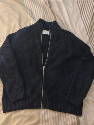 Mörkblå ribbstickad cardigan - Mörkblå cardigan från Vailent i storlek S utan några defekter och endast använd några fåtal gånger. Nypris ligger på ungefär 800 och jag säljer för 329kr