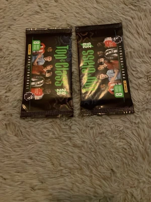 Top Class 2023 fotbollskort Premier League - Två oöppnade paket Top Class 2023 fotbollskort från Panini med Premier League-tema. Varje paket innehåller 8 samlarkort. Förpackningarna är svarta och gröna med bilder på kända fotbollsspelare och Premier League-loggan.