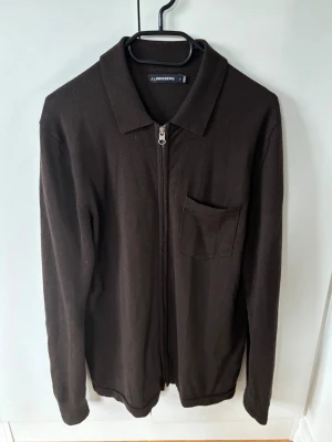 J.lindeberg 100% merino kofta - Sjukt snygg elegant och eftertraktad brun 100% merinoull cardigan/kofta från J.lindeberg i storlek M säljes. Perfekt nu till sommaren som ytterplagg och grym passform! I princip oanvänd så skicket är nästintill nytt! Inga hål eller fläckar och tröjan är i utmärkt tillstånd. 