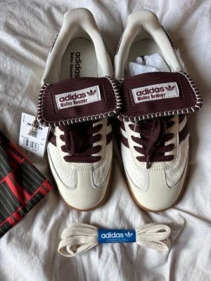 Adidas x Wales Bonner  - Adidas x Wales Bonner sneakers i vitt och vinrött. Helt nya aldrig använda. Storlek 42. Kommer med låda och dustbag.