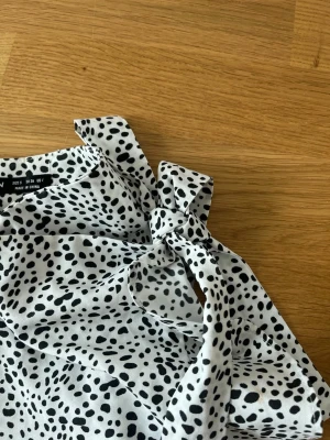 Prickig kjol med knyt från SHEIN - Snygg vit kjol från SHEIN med svarta prickar och trendig knytning vid höften. kjolen har ett lätt och luftigt material som känns skönt mot huden. Perfekt för dig som gillar ett lekfullt och stilrent mönster.