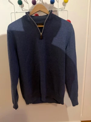 Blå halvzip tröja från Stenströms - Mysig blå tröja från Stenströms med halv dragkedja och ribbstickad krage. Perfekt för lager-på-lager och har en klassisk, stilren look. Materialet känns mjukt och passar bra till jeans eller chinos.
