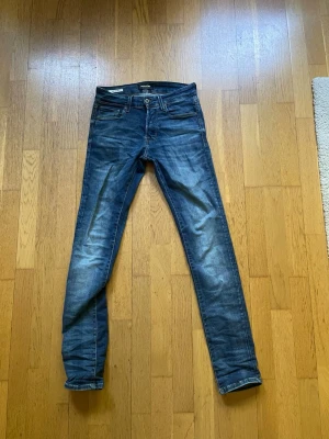 Mörkblå slim fit jeans från Jack & Jones  - Snygga mörkblå slim fit jeans från Jack & Jones med klassisk femficksdesign. Jeansen har normal midja och är tillverkade i stretchig denim för en bekväm passform. Perfekta för en trendig och avslappnad look.