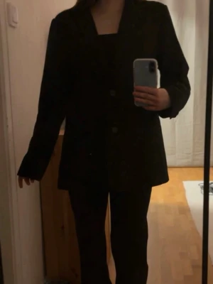 Svart kavaj från Gina Tricot - Stilren svart kavaj från Gina Tricot med klassisk krage och två knappar framtill. Köpt på vinted, så aldrig använd av mig personligen! Lite för lång för min smak. 