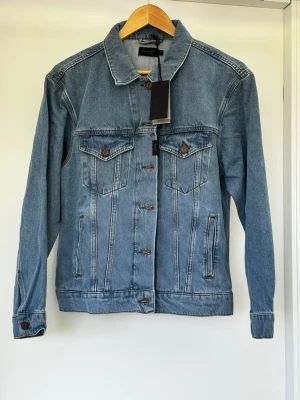 Helt ny jeansjacka i S-M från Seven7 - Helt ny o såklart oanvänd Seven7 Women’s  Denim Trucker Jeansjacka i S. (Amerikansk storlek och kan vara en aning större än EU-S), se gärna måtten nedan. Bilden med modellen är lånad. Axel: ca 49 Bröst: ca 54 Längd: ca 60.