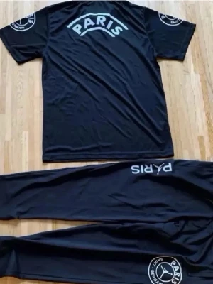 Svart loungewear-set Paris Saint-Germain - Säljer ett svart loungewear-set från Paris Saint-Germain med tryck 'PARIS' på både t-shirtens rygg och byxans framsida. Setet har logotyp på ärmen och byxbenet. Perfekt för chill dagar hemma. Materialet är mjukt och bekvämt.
