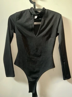 Svart långärmad body från NLY One - Säljer en svart body från NLY One i storlek XS. Bodyn har långa ärmar, hög krage och en djup v-ringning framtill. Ger en snygg passform tyvärr för liten för mig 