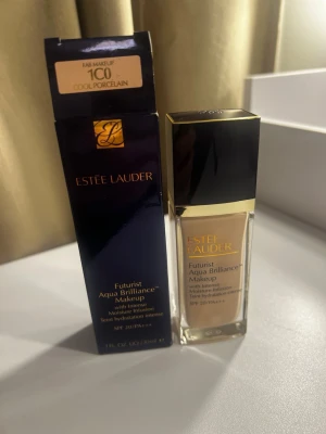 Estée Lauder Futurist Foundation 1C0 - Estée Lauder Futurist Aqua Brilliance Makeup i nyansen 1C0 Cool Porcelain. Flytande foundation i glasflaska med svart och guldfärgat lock. Ger intensiv återfuktning och har SPF 20. Perfekt för en naturlig och fräsch look.