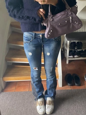 Lågmidjade bootcut jeans med revor - Midjemått: 38 cm rakt över 💓 Innerbenslängd: 82 cm 💓 Defekt visas i bild 5 (hål mellan benen främst vid rumpan) går att sy igen, men tyvärr har jag inte någon symaskin. Säljer pga för små. Ganska snyggt utsydda av min kompis, med svart jeans tyg så att jeansen passar en bootcut form! 🤗💕 