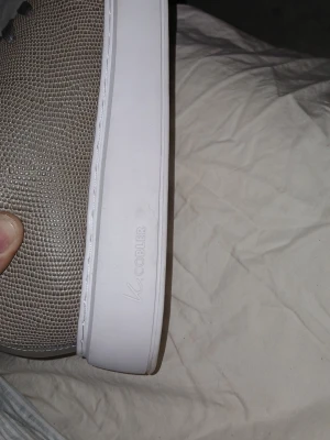 Grå sneakers från KCobler, storlek 41 - Snygga grå sneakers från KCobler med reptilmönstrad textur och vita sulor. Skorna har mörkgrå snören och en stilren design som passar perfekt till streetwear. Materialet är textil med struktur och sulan är i gummi.