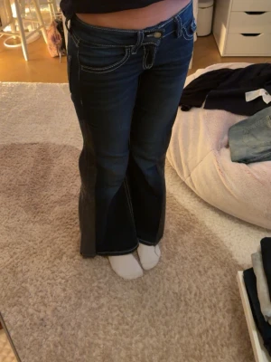 Mörkblå bootcut jeans med kontrastsömmar - Säljer ett par mörkblå bootcut jeans med vita kontrastsömmar och låg midja. Jag älskar dessa jeans med de är tyvärr lite för små, så jag säljer de.  Skriv vid frågor. Ge gärna prisförslag. Ni kan skriva om ni vill ha mått. 