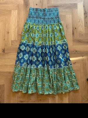 Mönstrad långkjol från Zara - Färgglad långkjol från Zara med blommigt och geometriskt mönster i blått, grönt och gult. Kjolen har resår i midjan och flera volanger för en bohemisk känsla. Står XS men skulle säga att den är mer som en S☺️
