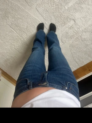 Blå bootcut jeans med låg midja - Snygga blå bootcut jeans med låg midja och klassisk femficksdesign. Jeansen har en lätt utsvängd passform nedtill och är tillverkade i ett slitstarkt denimtyg. Perfekta för en avslappnad och trendig look.