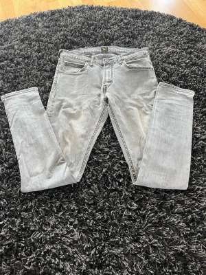 Grå jeans från Lee - Snygga grå jeans från Lee med klassisk femficksdesign och dragkedjegylf. Jeansen har en ljusgrå riktigt schysst tvätt! Hör av er vid frågor och funderingar! 