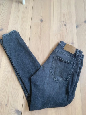 Grå slim fit jeans från Tiger of Sweden 29/32 - Säljer ett par snygga Snygga grå slim fit jeans från Tiger of Sweden med modellen pistolero. Jeansen är i grymt skick .Jeansen har en modern passform som sitter tight längs benen och är tillverkade i mjukt denimtyg med stretch för extra komfort.