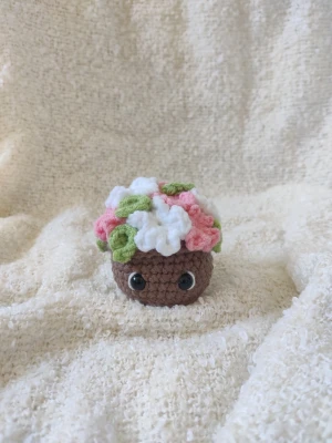 Virkad blomkruka  - Virkad blomkruka med rosa och vita blommor. Cirka 7 cm bred och 7 cm hög. Har tre likadana, därav tre annonser. 