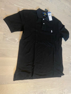 Svart pikétröja från Polo Ralph Lauren - Tja! Säljer en helt ny svart Ralph Lauren Piké.                      Den är helt ny och har inga hål eller fläckar.                                Storlek M och måtten kan du se på dem sista bilderna📐.                                                                              Priset kan diskuteras och jag skickar inom 24 Tim☺️💨