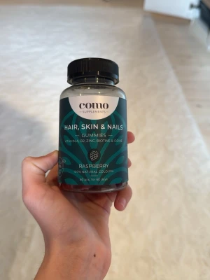 Como Hair, Skin & Nails Gummies - Burk med Como Supplements Hair, Skin & Nails Gummies med smak av hallon. Innehåller vitaminer som B12, B7, zink, biotin och jod. Vegansk formula med naturliga färger, 60 gummies i plastburk med svart lock, några är uppätna, men mer än hälften är kvar