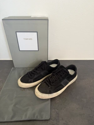 Svarta sneakers från Tom Ford stl 43 - Stilrena svarta sneakers från Tom Ford i mocka och lädermix. Klassisk låg modell med vita sulor och svarta skosnören. Kommer med originalkartong och dustbag. Perfekta för dig som gillar exklusiva och tidlösa sneakers.
