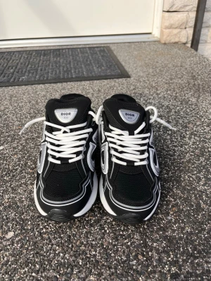 B30 - Snygga svarta Dor sneakers med vita och grå detaljer samt vita skosnören. Skorna har en chunky sula och meshpaneler för extra komfort. Stora loggor cd storlek 38