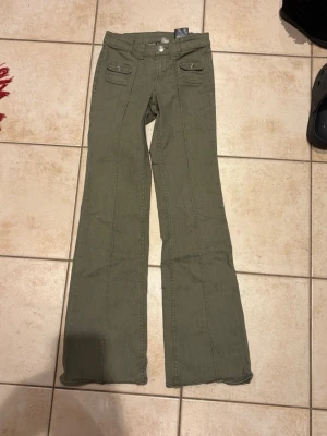 Poplulära jeans från h&m - Snygga olivgröna cargobyxor från Divided med raka ben och två fickor med lock framtill. Byxorna har en klassisk cargostil och är tillverkade i ett mjukt bomullsmaterial. Storlek 32. Bra skick