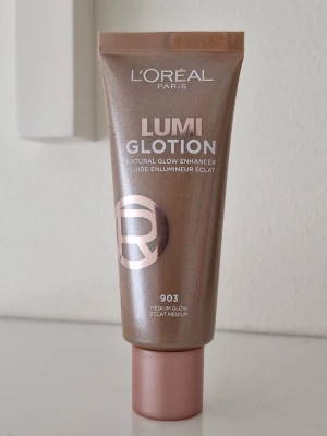 L'Oréal Lumi Glotion 903 Medium Glow - L'Oréal Lumi Glotion i nyansen 903 Medium Glow ger en naturlig lyster till huden. Tuben är guldig med roséguldfärgat lock och innehåller en flytande foundation som framhäver glow. Perfekt för dig som vill ha en fräsch och strålande look. Endast testad. 