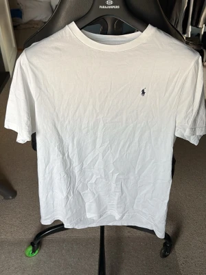 Vit t-shirt från Ralph Lauren - Klassisk vit t-shirt från Ralph Lauren. Morsan köpte fel storlek så den är helt oanvänd. Perfekt basic-plagg i mjuk bomull som funkar till allt.