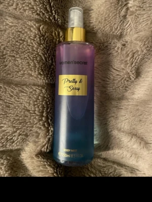Women'secret Pretty & Sexy Body Mist - Body mist från Women'secret i doften Pretty & Sexy. Flaskan är i plast med en snygg färgskiftning från lila till blå och har en guldfärgad kork. Rymmer 250 ml och har en praktisk sprayfunktion. Perfekt för dig som vill ha en fräsch och lätt doft.