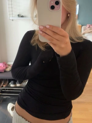 Intimissimi - En enkel och stilren svart långärmad topp med tight passform. Toppen har rund halsringning och är tillverkad i ett mjukt material som sitter skönt mot kroppen. Perfekt att matcha med jeans eller kjol för en clean look.