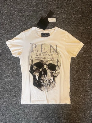 Philipp Plein T-shirt (limiterad) - Vit t-shirt från Philipp Plein i bra skick. Köpt på Miinto 2024.                                                  -Nypris låg runt 2000-5000kr (När den var tillgänglig senast 2025)                                                        -Skick: 8/10                                                                                 Hör av dig vid frågor och funderingar!