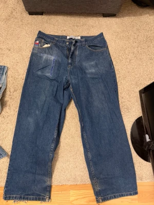 Polar skate bigboy  - Säljer ett par blåa loose fit jeans med raka ben och hög midja. Jeansen har en liten patch på fickan och en markerad söm i blått på ena benet. Perfekta för en avslappnad streetstil.