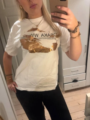 Vit t-shirt med tryck - ‼️SÄLJER INTE FÖR MINDRE‼️Vit t-shirt med coolt guldtryck och svart text framtill. Klassisk passform med rund hals och korta ärmar. Perfekt för dig som vill sticka ut lite extra med metallic-detaljer💗💗
