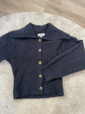 Stickad  tröja  - Mysig mörkblå tröja från Gina Tricot. Koftan har stora knappar framtill, bred krage och lång ärm. Perfekt för lager på lager och enkel att styla till olika outfits.