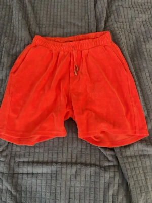 Röda frottéshorts med snörning - Snygga röda shorts i mjuk frotté med elastisk midja och snörning framtill. Shortsen har sidofickor och en bakficka, perfekt för en chill sommardag. Sköna och avslappnade med loose passform.