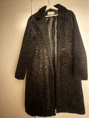 Svart lång teddykappa - Säljer en svart lång teddykappa från NLY TREND med mjukt, fluffigt material. Jackan har helsvart foder och raka ärmar. Perfekt för dig som vill ha en trendig och mysig look under kalla dagar.