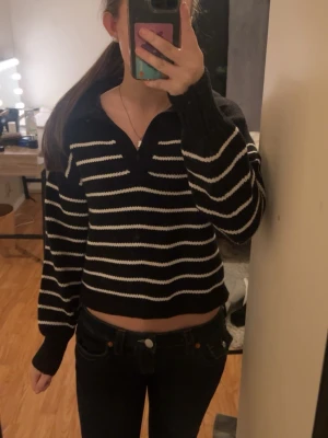 Svartvitrandig stickad tröja - Säljer en svart stickad tröja med vita ränder som är v ringad. 
