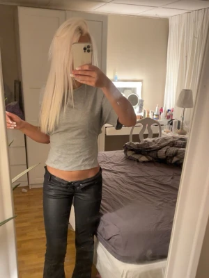 Grå croppad topp med knytband - Säljer en ljusgrå croppad topp med rund hals och korta ärmar. Toppen har snygga knytband i sidorna som ger en unik look. Perfekt till jeans eller kjol för en chill och trendig stil.