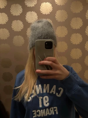 Grå fluffig mössa i ullmix - Säljer en supermjuk och fluffig grå mössa i ullmix. Mössan har en enkel, rak modell och sitter skönt på huvudet. Perfekt för kalla dagar när du vill hålla dig varm och ändå se snygg ut.