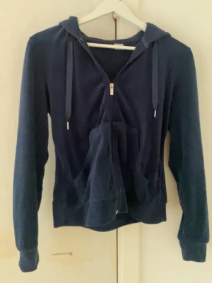 Mörkblå zip hoodie med huva - Mörkblå hoodie med dragkedja framtill. Tröjan har huva med dragsko och ribbade muddar vid ärmslut och nederkant. Snören framtill av silke. Perfekt för en avslappnad och chill stil. Från Gina Tricot 