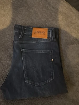 Mörkblå jeans från Replay - Snygga mörkblå jeans från Replay med klassisk femficksmodell och diskreta slitningar. Jeansen har en läderpatch med Replay-logga bak i midjan och detaljerade sömmar. Tillverkade i stretchigt denim för skön passform. Model slim fit