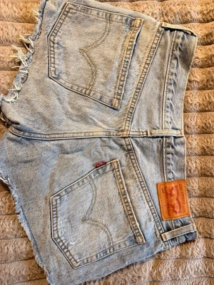 Levi's ljusblå jeansshorts lågmidja  - Säljer ljusblå jeansshorts från Levi's med låg midja. Storlek: W27 som motsvarar 38cm över midjan.