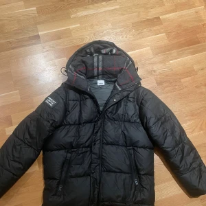 Burberry jacka - Säljer en svart pufferjacka från burbery. Riktigt fet och sjukt varm. Perfekt för dig som gillar komfort men också prioriterar stil. Inga skavanken över huvudtaget. Knappt använd.