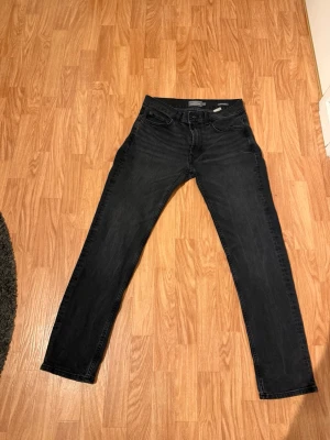 Svarta jeans - Snygga svarta slim fit jeans med klassisk femficksdesign och raka ben. Jeansen har subtila slitningar och är tillverkade i ett mjukt denimtyg med lite stretch för extra komfort. Perfekta till en avslappnad streetwear-look.