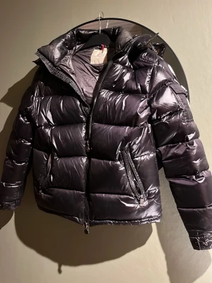 Moncler jacka  - Säljer nu dotterns Moncler jacka i modell Maya!Storlek S (vilket är lika med 1 som står på jackan) jackan är använd men är i perfekt skick. Tjock och värmande och mycket bekväm. Förpackning och prislapp tillkommer. Jackan är unisex så både till dam och herr. Skriv för mer bilder eller andra frågor! 